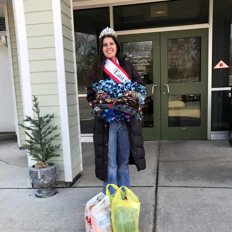 Woman holding a stack of animal supplies and donations.