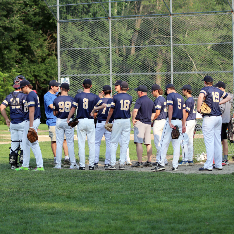 Group of baseball players listening to their coach speak on the field.