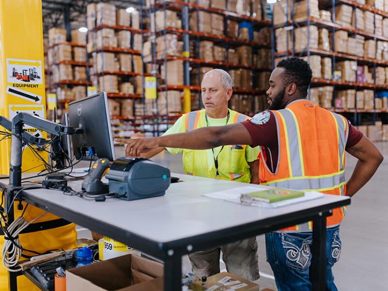 Image of two warehouse workers pointing to computer screen at an ecommerce fulfillment center