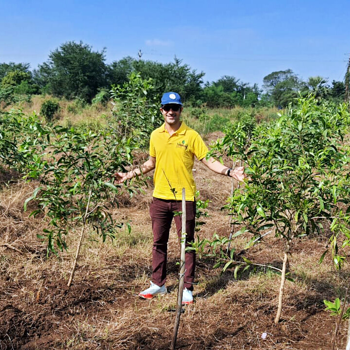Man standing in front of tree saplings.