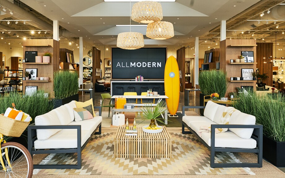Two white couches sit on either side of a crate table -- behind, you see a sprawling, warm store with wood and yellow accents.