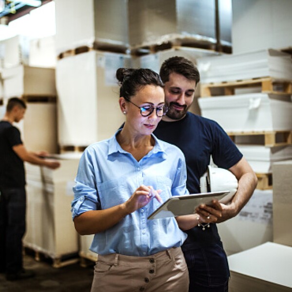 Suppliers at warehouse looking on ipad for logistics management