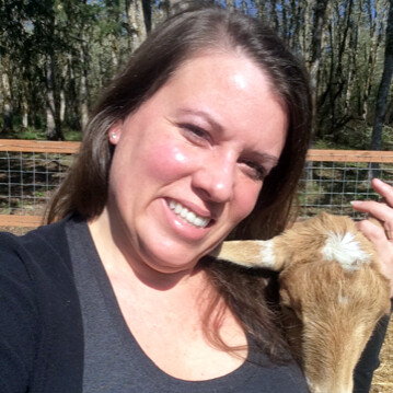 Woman posing with baby goat.