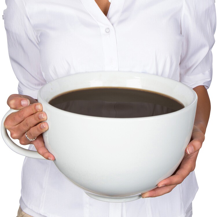 Person in white shirt holding a very large white ceramic coffee cup.