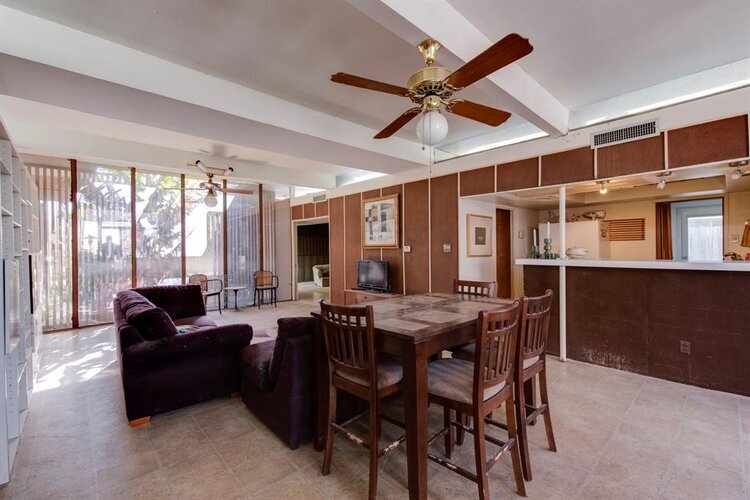 A "before" photo of the previous room, which is more sparse, and shows a brown kitchen island with brown stools.