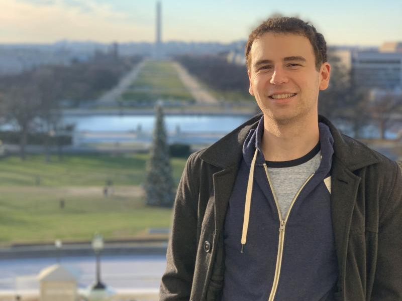 A photograph of Wayfair Engineer Adam Carlson smiling at the camera with his hands in his pockets.