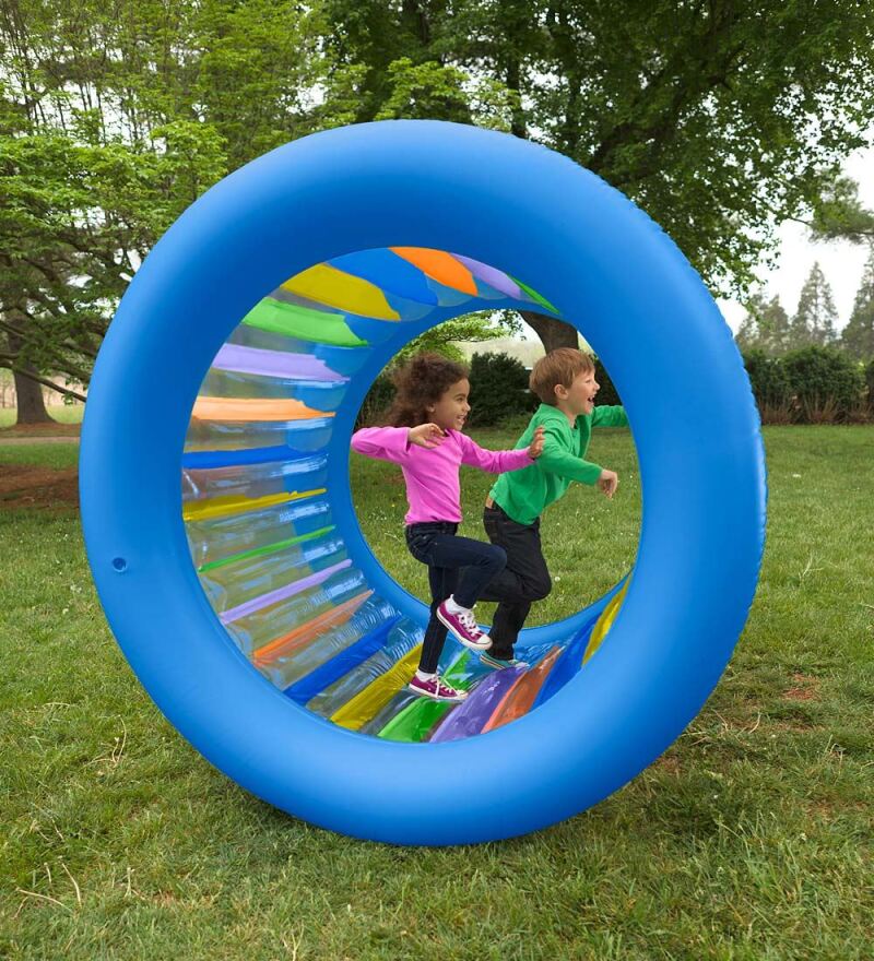 Two children running on a rubber inflatable human hamster wheel.