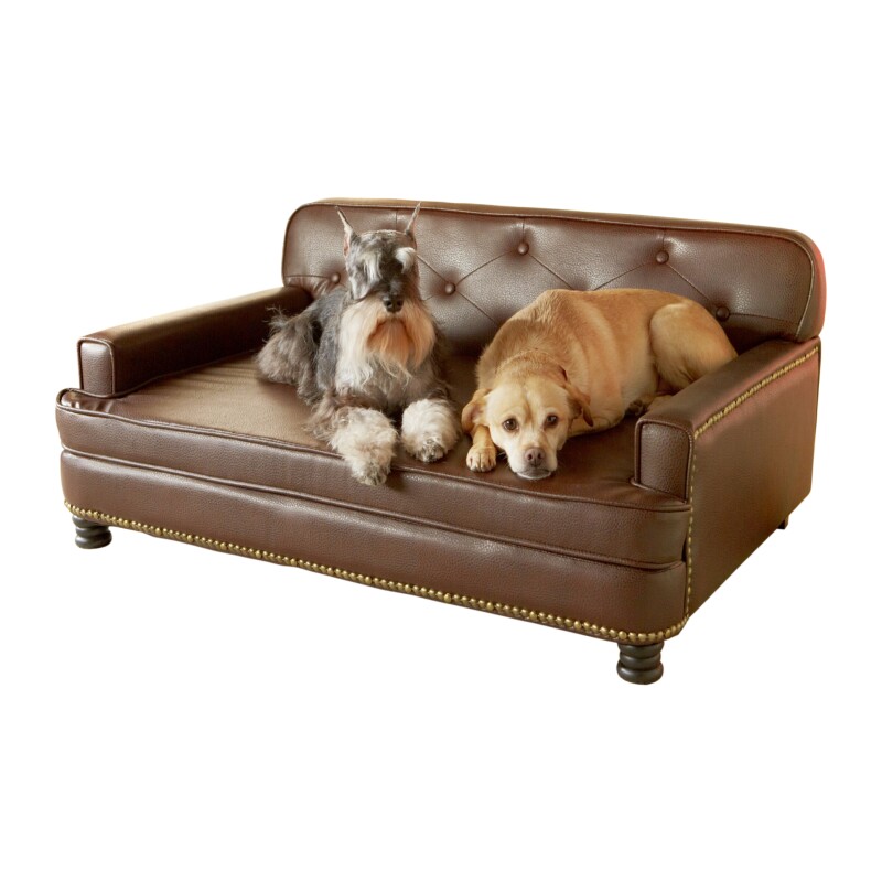 Two dogs laying on a miniature brown leather couch.
