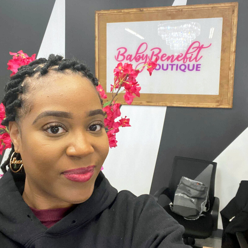 Woman smiling in front of sign that reads "Baby Benefit Boutique."
