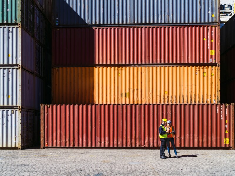 Workers having discussion against cargo containers