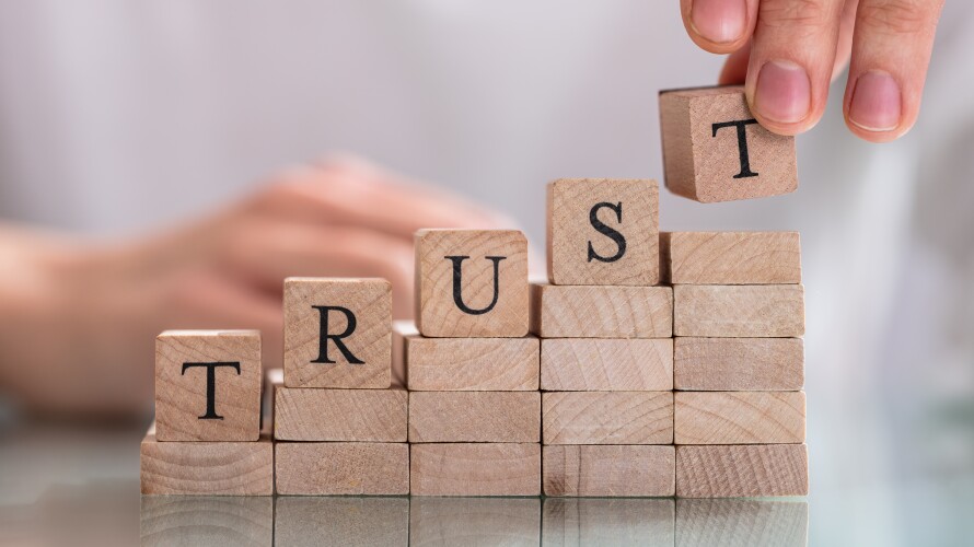 Woman's Hand Placing Last Alphabet Of Word Trust