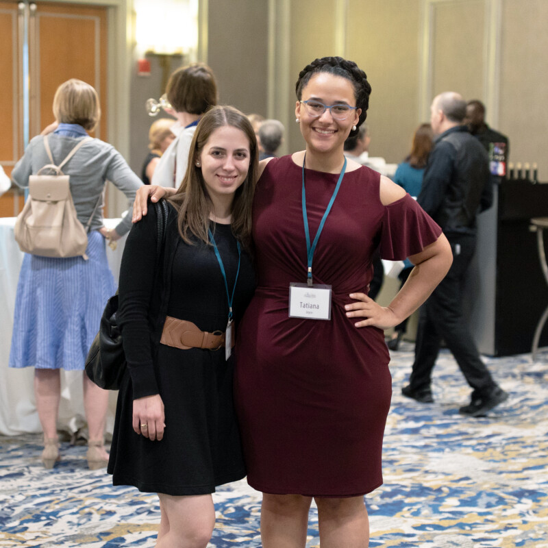 Two women standing at a conference smiling for the camera.